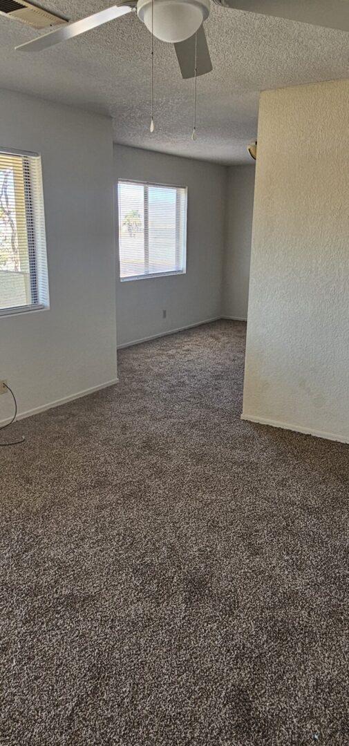 Empty carpeted room with ceiling fan.