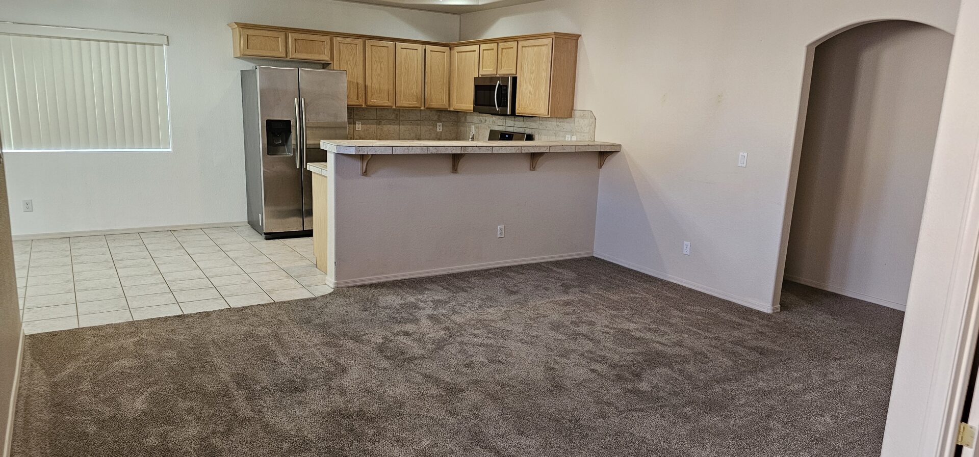 Empty apartment living room with kitchen.