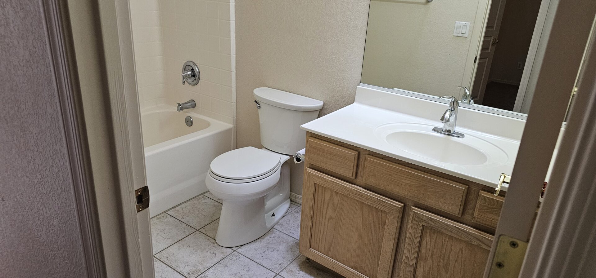 Small bathroom with tub, toilet, and vanity.