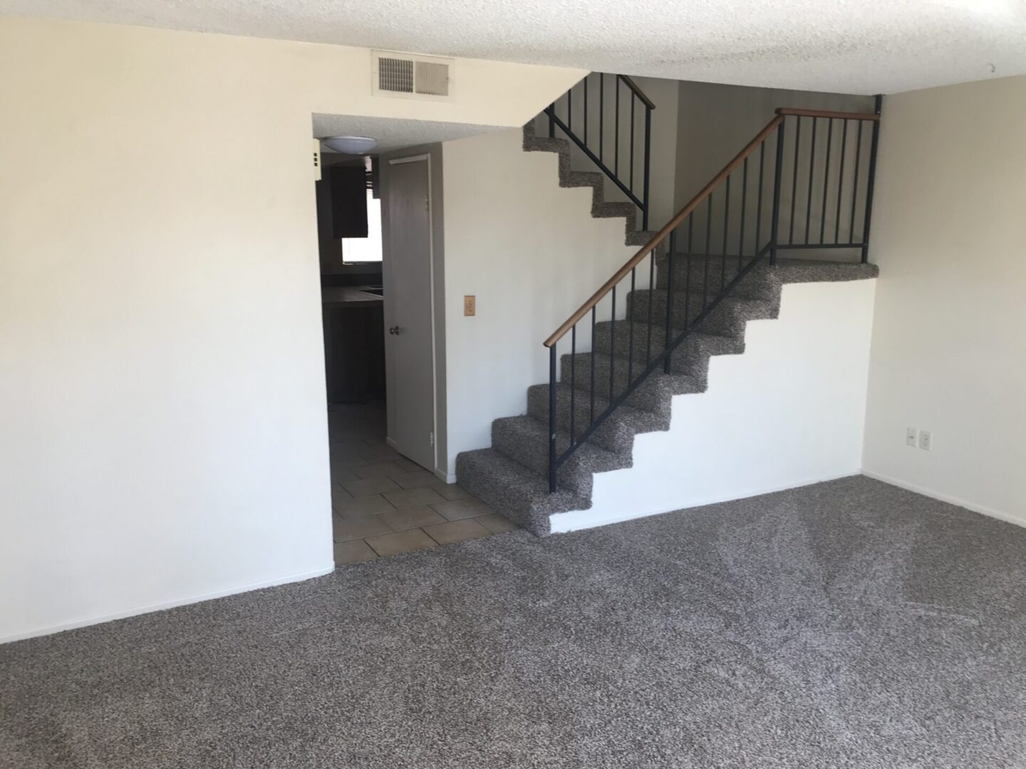Carpeted living room with stairs.