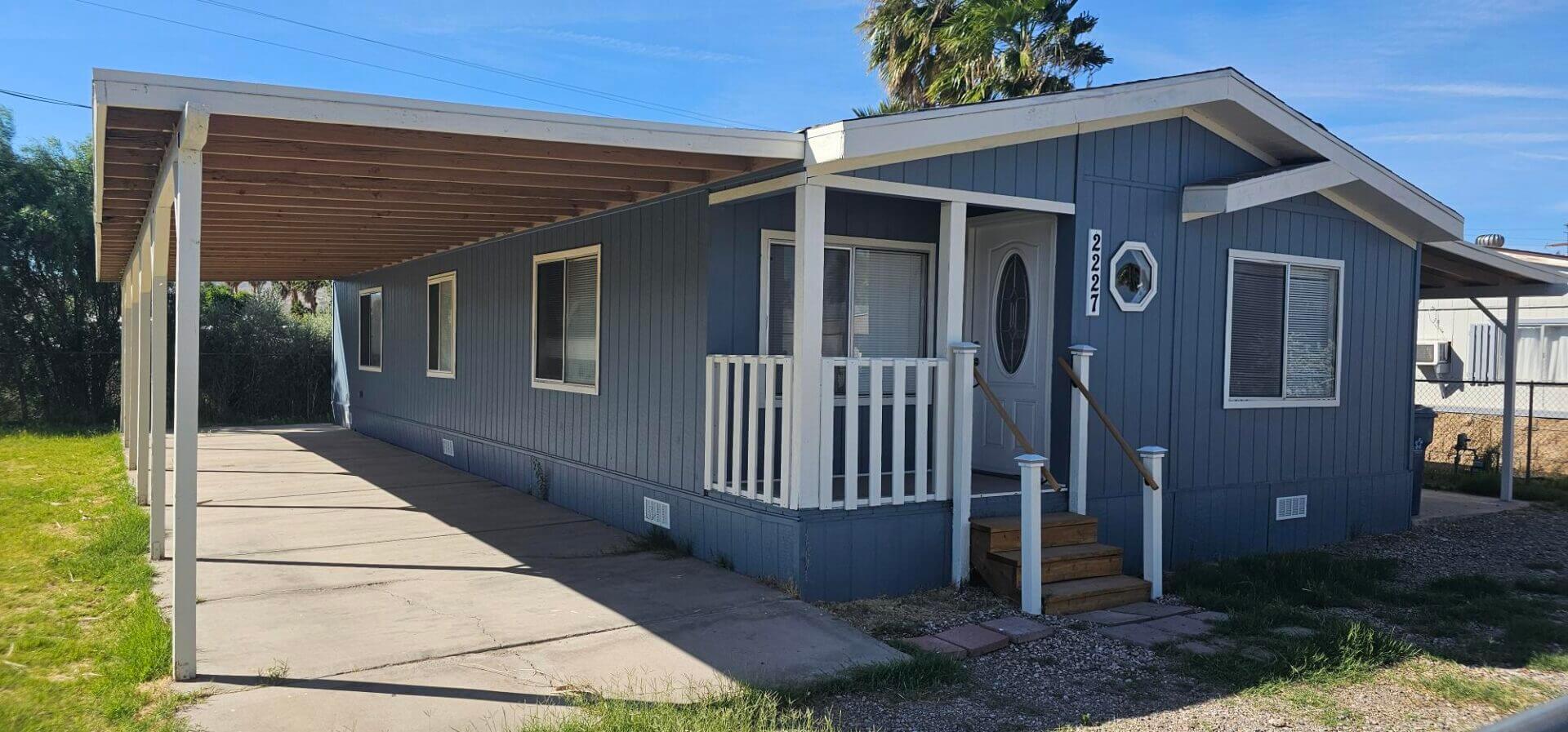 Blue mobile home with covered carport and porch