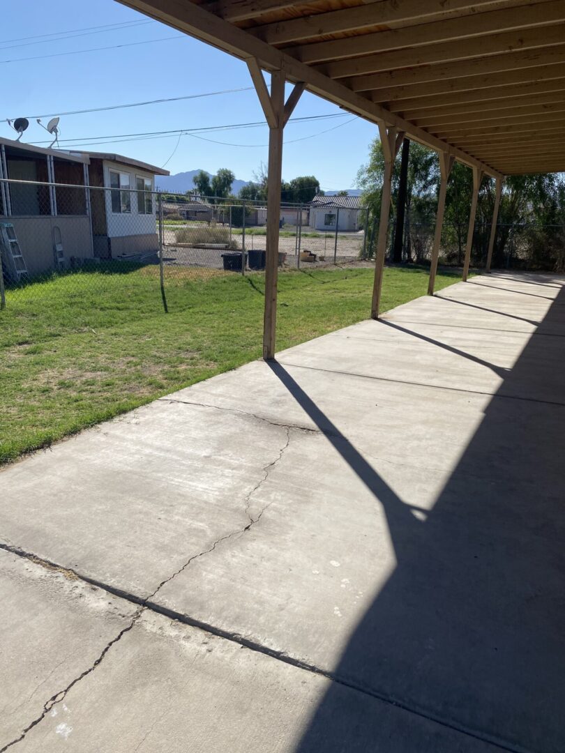 Covered patio with concrete walkway and yard