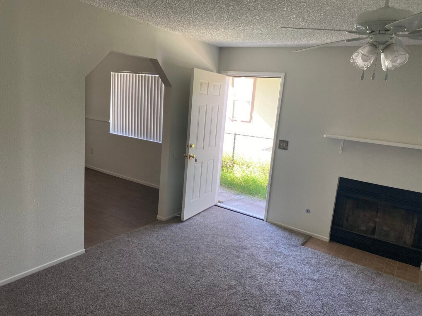 Empty living room with open door and fireplace